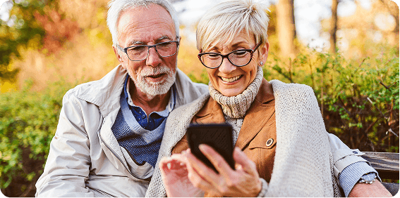 Senior couple sitting in park and chatting about Medicare Advantage
